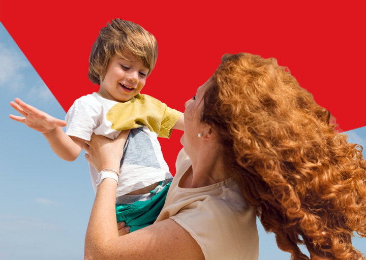 Photo d’une mère soulevant joyeusement son enfant vers le ciel illustrant l'impact positif de la Banque Nationale dans la vie des gens 