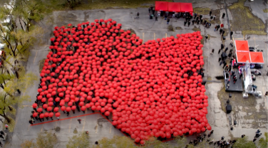 Photo en plongée d’un groupe de gens tenant des parapluies rouges pour former le logo de la Banque Nationale