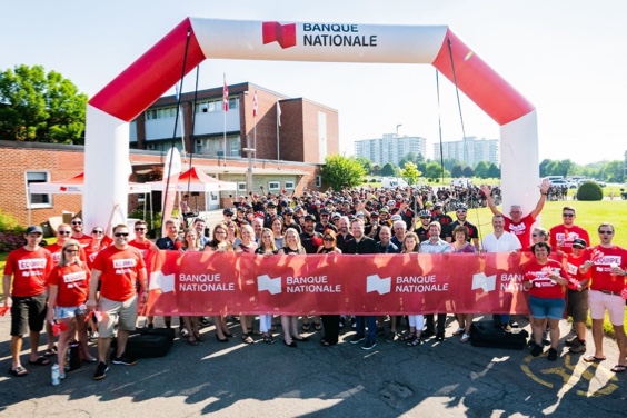 Photo d’un groupe d’employés vêtus de rouge tenant une banderole au logo Banque Nationale à la fin d’une course 