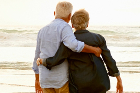 Couple de retraités qui se serre dans les bras face à la mer