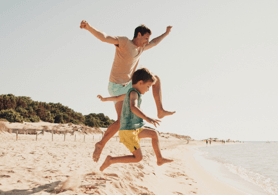 Photo d'un père et d'un fils sautant de joie à la plage