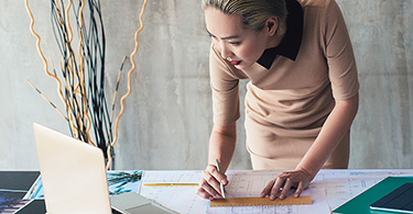 Photo d'une femme traçant un plan sur une table de travail