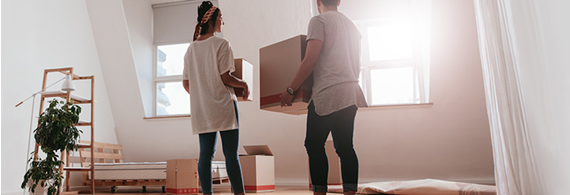 Jeune couple porte des boîtes dans une maison vide
