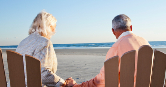 Couple de retraités se tiennent la main face à la mer