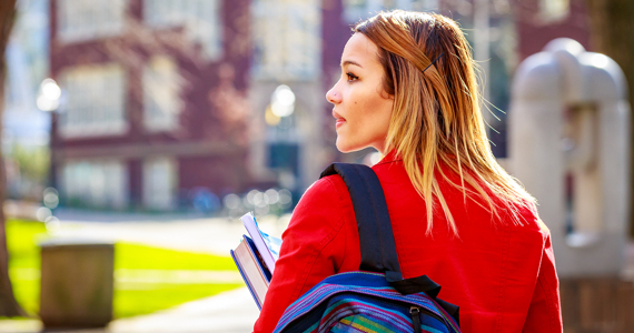 Jeune étudiante avec sac à dos marche sur un campus universitaire