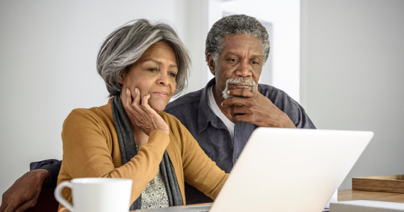 Couple de retraités réfléchissent en regardant un ordinateur portable