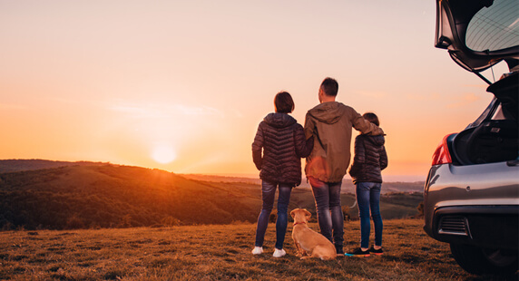 Famille observant le coucher de soleil en haut d'une colline