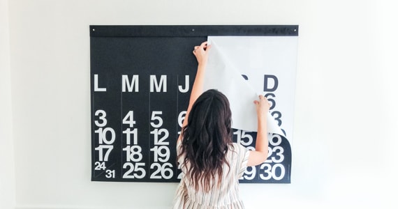 Photo d'une femme retirant une page d’un grand calendrier accroché au mur