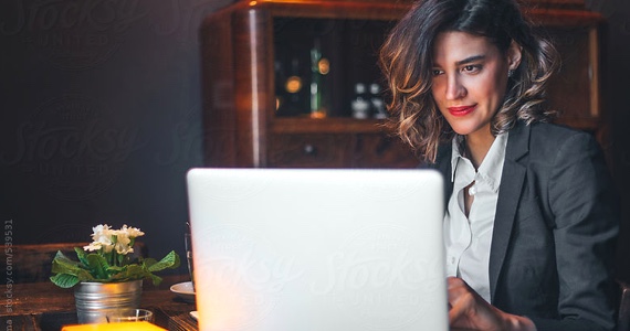 Jeune femme professionnelle sourit en travaillant à son ordinateur 