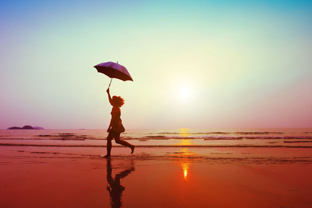 Jeune femme courant sur la plage devant un coucher de soleil  