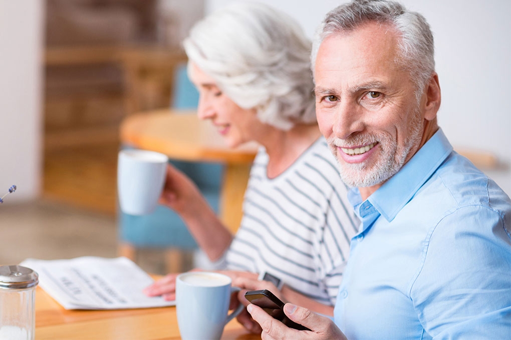 Photo d’un couple de retraités assis à une table avec une tasse de café à la main 