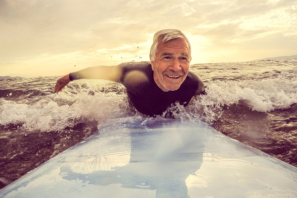 Homme retraité souriant sur une planche de surf