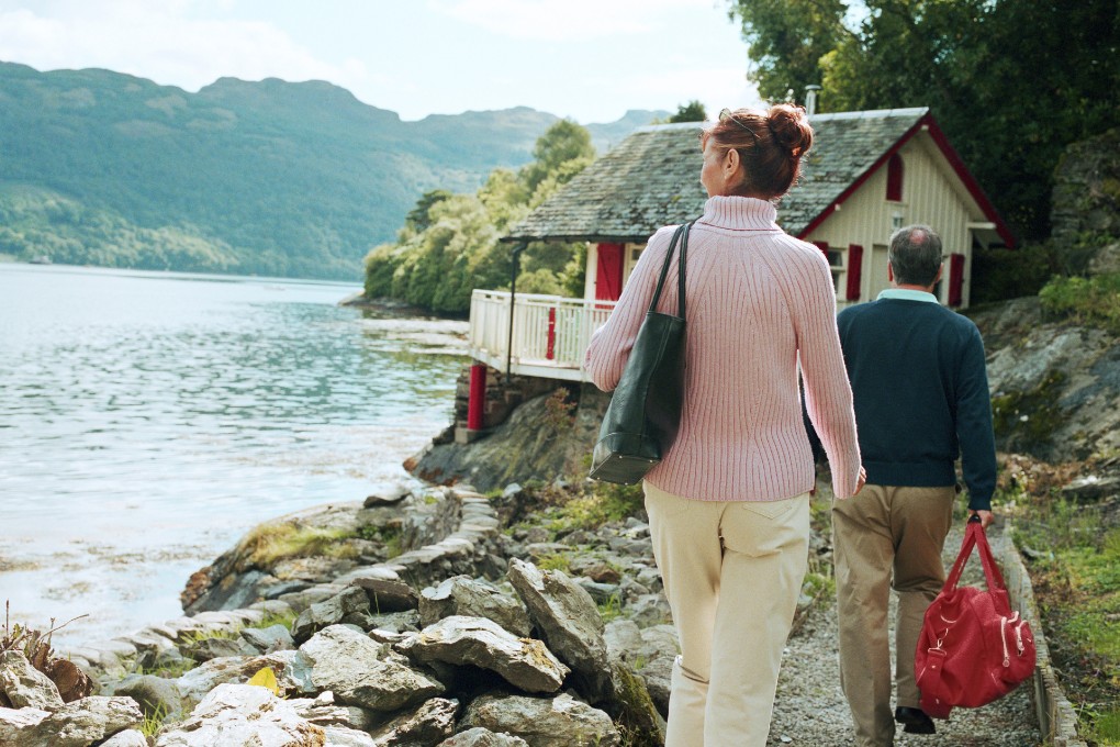 Couple de retraités marchant vers un chalet au bord de l’eau.