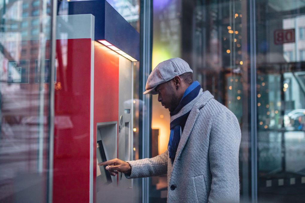 Photo d’un homme effectuant une transaction dans un guichet bancaire 
