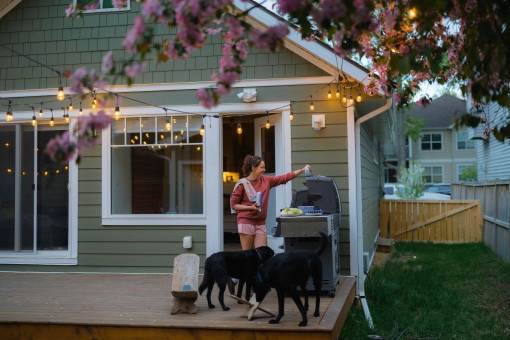 Femme devant sont BBQ sur la terrasse de sa nouvelle maison