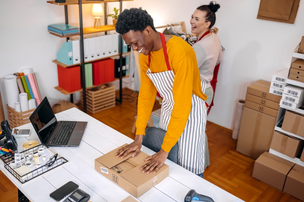 Image pour l’article sur le démarrage d’entreprise illustrant un homme emballant un colis et sa collègue riant ensemble