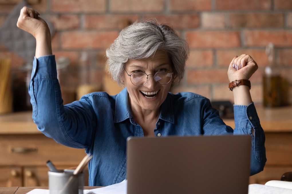Une investisseuse éclate de joie après avoir fait un prêt de titres ou d’actions sur son ordinateur.