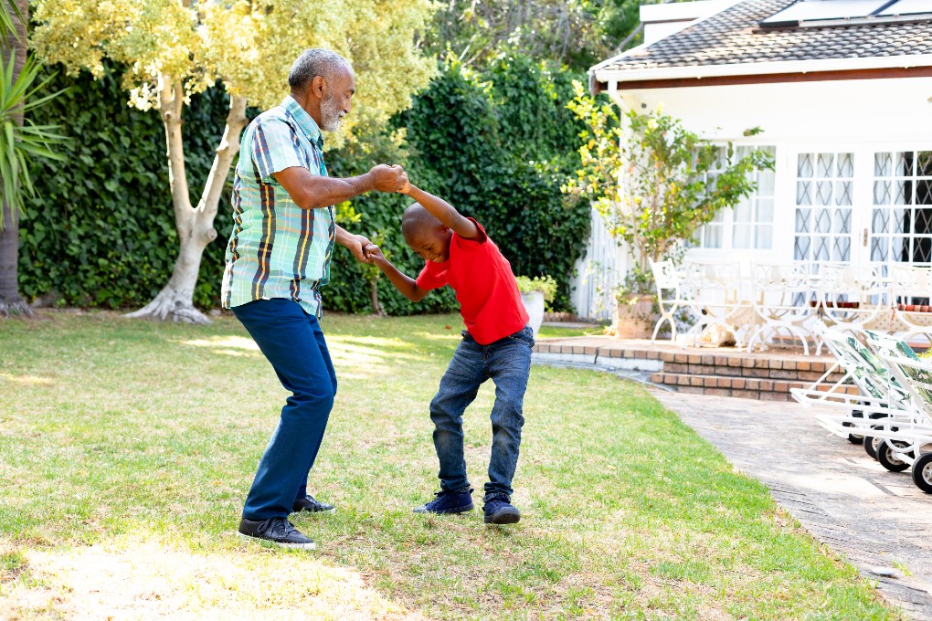 Un grand-père et son petit-fils dansent dans le jardin familial.