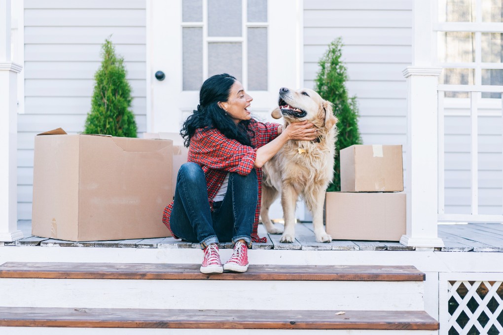 Jeune femme avec son chien sur le parvis de sa première maison