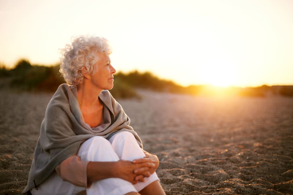 Une femme retraitée regarde le coucher de soleil sur la plage en floride
