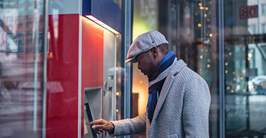 Photo of a man completing a transaction at an automatic banking machine
