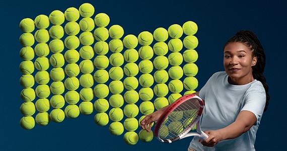 Photo d’une fille souriante tenant sa raquette de tennis derrière elle