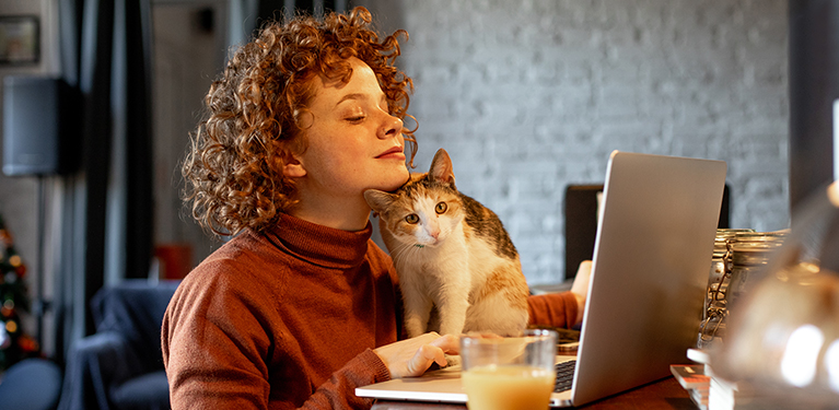 Photo d’une personne avec un chat devant un ordinateur 