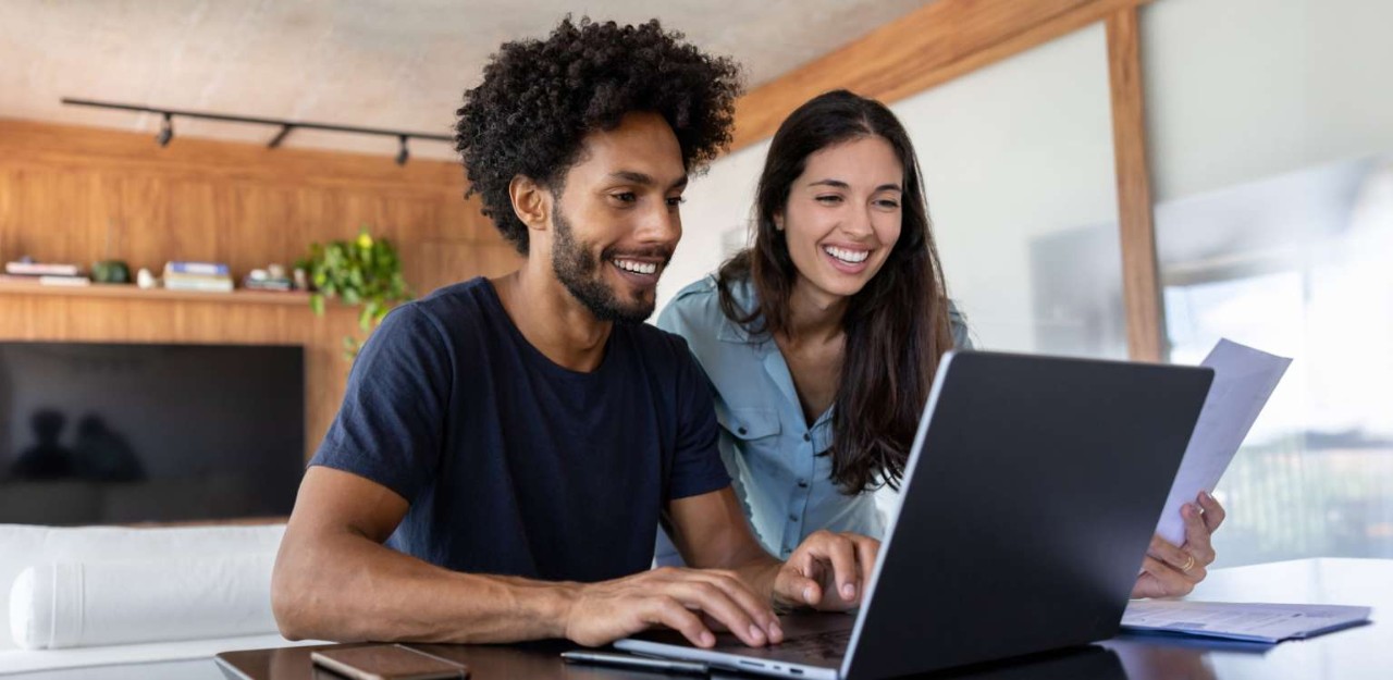 Photo de deux personnes regardant un ordinateur en souriant