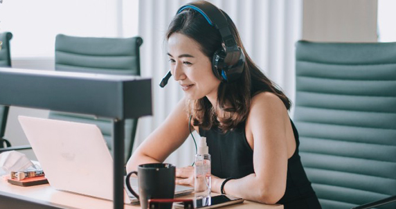 Photo d'une femme avec casque d'écoute qui participe à une réunion virtuelle dans une salle de conférence